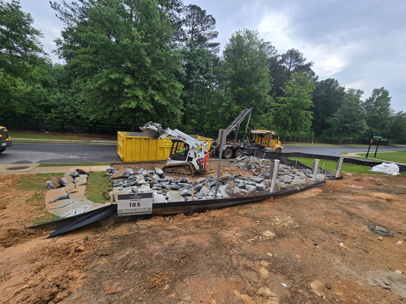 Skid steer loading concrete debris into Alnico container