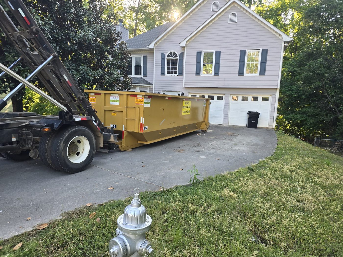 Roll off truck dropping container on residential driveway