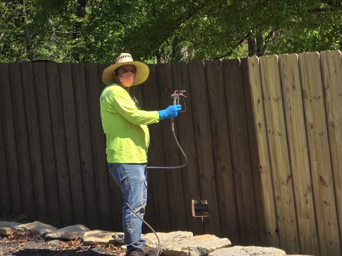 Crew member spray staining a wooden fence